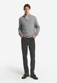 Grå kvartdraget tröja med ribbade ärmavslut, i kombination med mörka jeans och mörka skor. Snygg textur, avslappnad passform, minimalistisk design.