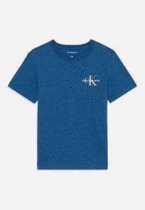 Lyhythihainen, pyöreäkauluksinen T-paita, jossa on tummansininen puuvilla ja pieni valkoinen "Calvin Klein Jeans" -logo rinnassa. Tasainen pinta.