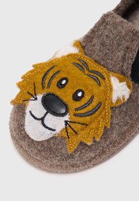 Zapatilla de felpa gris con aplicación de cara de tigre en marrón, negro y blanco, con detalles cosidos y suaves acentos en las orejas.