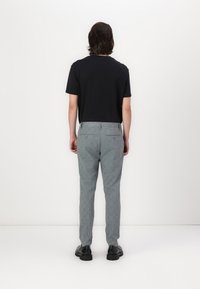 Black short-sleeve t-shirt paired with gray check-patterned pants. The outfit is completed with black shoes, viewed from the back.