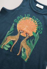 Tumesinine top, millel on kujutis kahest leopardist kõrval stiliseeritud oranži viiluga ja roheliste lehtedega, tekstiga „Solar Dreams“.