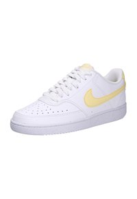 Le sneakers Nike presentano una tomaia in pelle bianca con un Swoosh giallo, punta rotonda, dettagli perforati e una suola in gomma bianca testurizzata.
