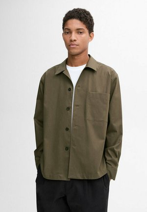 Camicia verde oliva in tessuto leggero con abbottonatura frontale, colletto a punta e una tasca sul petto. Realizzata in materiale traspirante.