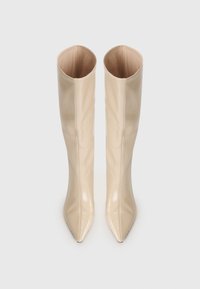 Beige, glossy over-the-knee boots with a pointed toe and sleek, smooth texture; interior is a contrasting soft material.