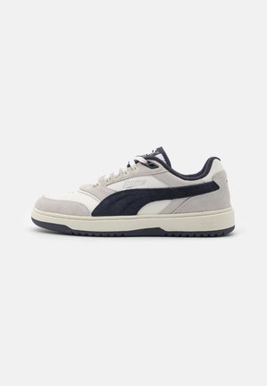 Sneakers Puma in una combinazione di colori beige e blu navy, realizzati in materiali scamosciati e in pelle, con design low-top e suola in gomma testurizzata.