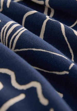 Marineblauer Stoff mit weißen abstrakten Mustern; weiche Textur mit Falten, die Tiefe erzeugen; der Fokus liegt auf glatten Linien und Formen im Design.
