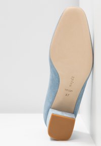 Chaussure plate en daim bleu clair, vue de la semelle, avec un talon beige et la taille 37 marquée.