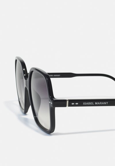 Zwarte oversized vierkante zonnebril met gradientlenzen en het "ISABEL MARANT" logo op de pootjes tegen een witte achtergrond.