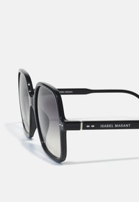 Ochelari de soare negri, supradimensionați, cu un design pătrat, lentile în degrade, și brațe marcate cu accente argintii și o finisare lucioasă.