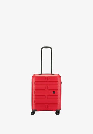 Valigia rigida rossa con forma rettangolare, superficie testurizzata con scanalature orizzontali, manico nero retrattile e quattro ruote.