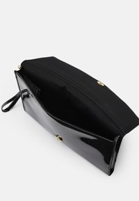 Zwarte patentleren clutch met een gouden drukknoopsluiting. Interieur is voorzien van zwarte stofvoering en een polsband aan één kant.
