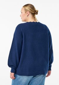 Navy blue knitted sweater with a relaxed fit, scalloped neckline, and balloon sleeves. Textured fabric with ribbed hem detail.