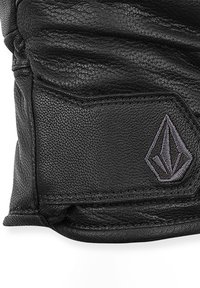 Gant en cuir noir avec une finition texturée, présentant un design cousu et un petit logo gris accentuant la zone du poignet.