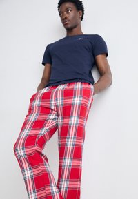 Røde ternede pyjamabukser med blå og hvide striber, kombineret med en marineblå T-shirt. Blødt stof med elastisk talje. Slim-fit design.