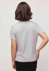Sivá krátkobjedná tričko s okrúhlym výstrihom, uvoľneným strihom a mäkkou textúrou, z pohľadu zozadu so viditeľnými švovými detailmi.