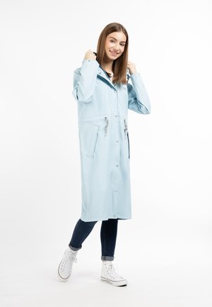 Light blue waterproof coat with a fitted design, snap button closure, side pockets, and adjustable drawstring hood, paired with jeans and sneakers.