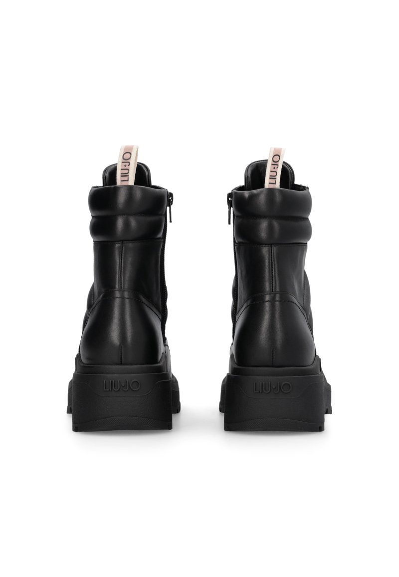 Botas de tobillo de cuero negro con un diseño acolchado, punta redondeada, cremallera trasera y una suela de plataforma texturizada con un detalle de logo.