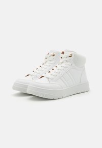 Białe sneakersy za kostkę wykonane ze skóry, z teksturowanym kołnierzem przy kostce, złotymi oczkami, perforowanymi akcentami i teksturowaną gumową podeszwą.