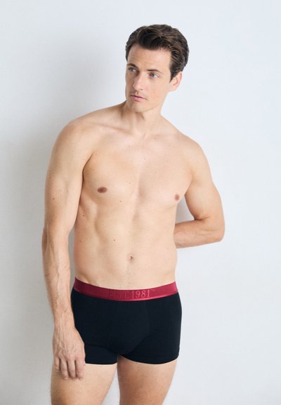 Boxeri negri din bumbac cu un elastic închis la culoare, de burgundă. Elasticul are inscripționat textul "EST 1981" într-o culoare contrastantă. Textură netedă.