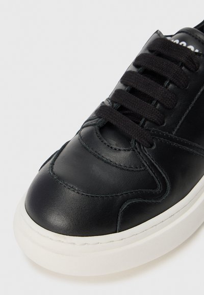 Svarta lädersneakers med rund tå, utrustade med svarta snören, vit gummisula och subtila sömdetaljer. Slät yta överlag.