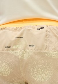 Μπεζ σορτς για τρέξιμο με μικρά διακριτικά σχέδια, τσέπη με φερμουάρ και το κείμενο «Nike Running Distant Dreams» στη ζώνη της μέσης.