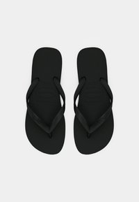 Une paire de tongs en caoutchouc noir uni avec des semelles texturées et des sangles marquées, affichées côte à côte sur un fond blanc.