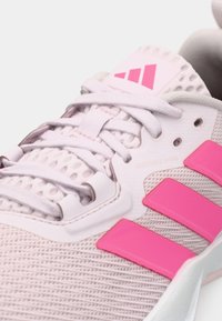 Lys rosa treningssko med øvre del i strukturert mesh, rosa aksentstriper, justerbar snøring og en gummisåle.