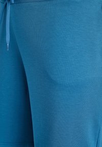 Blaue Sportshorts aus weichem, atmungsaktivem Stoff mit Kordelzug in der Taille und glatter Textur, mit schlichtem Design ohne Muster.