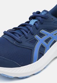 Scarpa sportiva blu navy con tomaia in rete, accenti blu e azzurri, stringhe navy e suola bianca, progettata per la corsa o sport.
