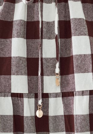 Rood en wit geruite stof met een gestructureerde weving. Bevat trekkoorden met gouden hardware en een geplooide zoom.