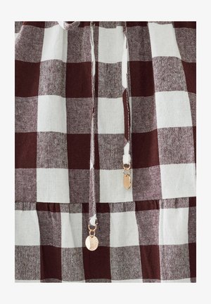 Rood en wit geruite stof met een gestructureerde weving. Bevat trekkoorden met gouden hardware en een geplooide zoom.