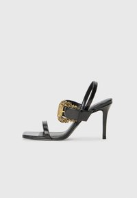 Black leather high-heeled sandals featuring a square toe, two thin straps, and a decorative gold buckle with ornate detailing on the side.