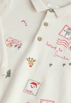 Tejkrém színű kötött polo ing, amely karácsonyi motívumokkal van hímezve: szarvasmarha, hóember, cukorbot és piros-zöld színű szöveg. Három gomb.