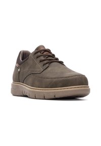 Zapatos de cuero verde oscuro con una textura suave, cordones marrones y una suela de goma color marrón claro. Presentan un diseño cosido en la parte superior.
