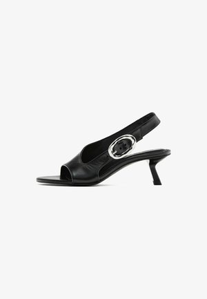 Czarne skórzane buty typu slingback z otwartym palcem, smukłym obcasem i srebrnym detalem z klamrą na pasku. Gładka tekstura i elegancki design.