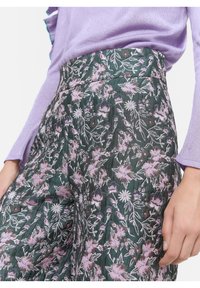 Blommönstrade byxor i grönt med lila blommig broderi, hög midja, texturerad tyg och plisserad frontdetalj.