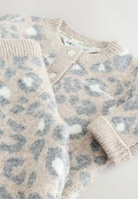 Pletený vlněný cardigan s leopardím potiskem v béžové, šedé a bílé barvě. Má žebrované manžety, zapínání na knoflíky a měkkou texturu.