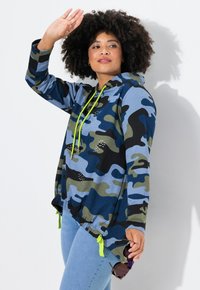 Felpa camouflage blu e verde con cordino, dettagli decorativi e vestibilità rilassata; presenta un orlo arricciato con legature verde brillante.