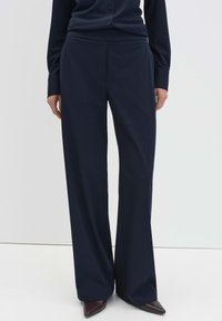 Marineblauwe wijde broekspijpen van glad, zacht materiaal; heeft een getailleerde pasvorm, een voorzak en subtiele plooien voor een gestroomlijnde uitstraling.