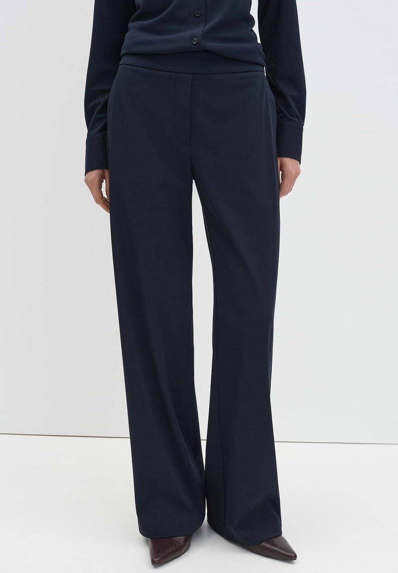 Marineblauwe wijde broekspijpen van glad, zacht materiaal; heeft een getailleerde pasvorm, een voorzak en subtiele plooien voor een gestroomlijnde uitstraling.