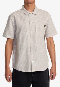 Short-sleeve button-up shirt in white with narrow red stripes, featuring a chest pocket and a square tag on the pocket. Cotton fabric.
