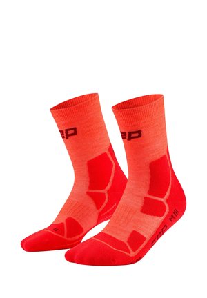 Pair of bright orange athletic crew socks with red cushioned areas and black branding on a white background.