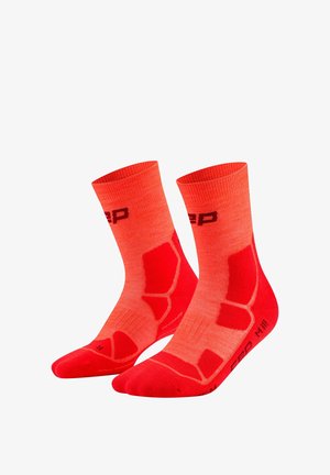 Pair of bright orange athletic crew socks with red cushioned areas and black branding on a white background.