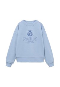 Ljusblå sweatshirt med rund halsringning, sänkta axlar och ribbade muddar. Har broderad text "PARIS" och kronlogotyp.