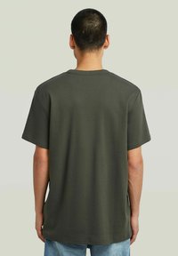 Groene katoenen t-shirt met korte mouwen, ronde hals en een relaxed fit. Gladde textuur zonder patronen. Zicht van achteren.