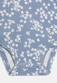 Kurzarm-Babybody aus blauem Baumwollstoff mit kleinem weißen Blumenmuster. Verfügt über Druckknöpfe im Schritt und eine weiche Textur.