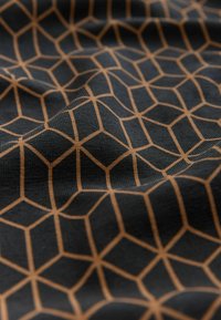 Fekete szövet, világosbarna geometrikus méhsejt mintával, amely texturált felületet mutat be, lágy, szőtt megjelenéssel.