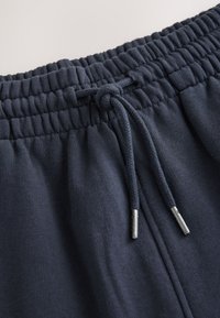 Marinblå sweatpants med resår i midjan och justerbar dragsko. Mjuk textur och silverfärgade metalländar på dragskon.