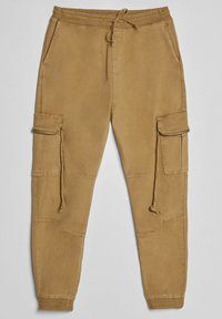 Beige cargojoggers med resår i midjan, sidofickor och dragkedjor. Tillverkade av mjuk bomull, med en tapered ben-design.
