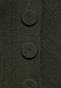 Tissu tricoté vert foncé avec trois grands boutons recouverts alignés verticalement, montrant une texture de tricot détaillée et des coutures.